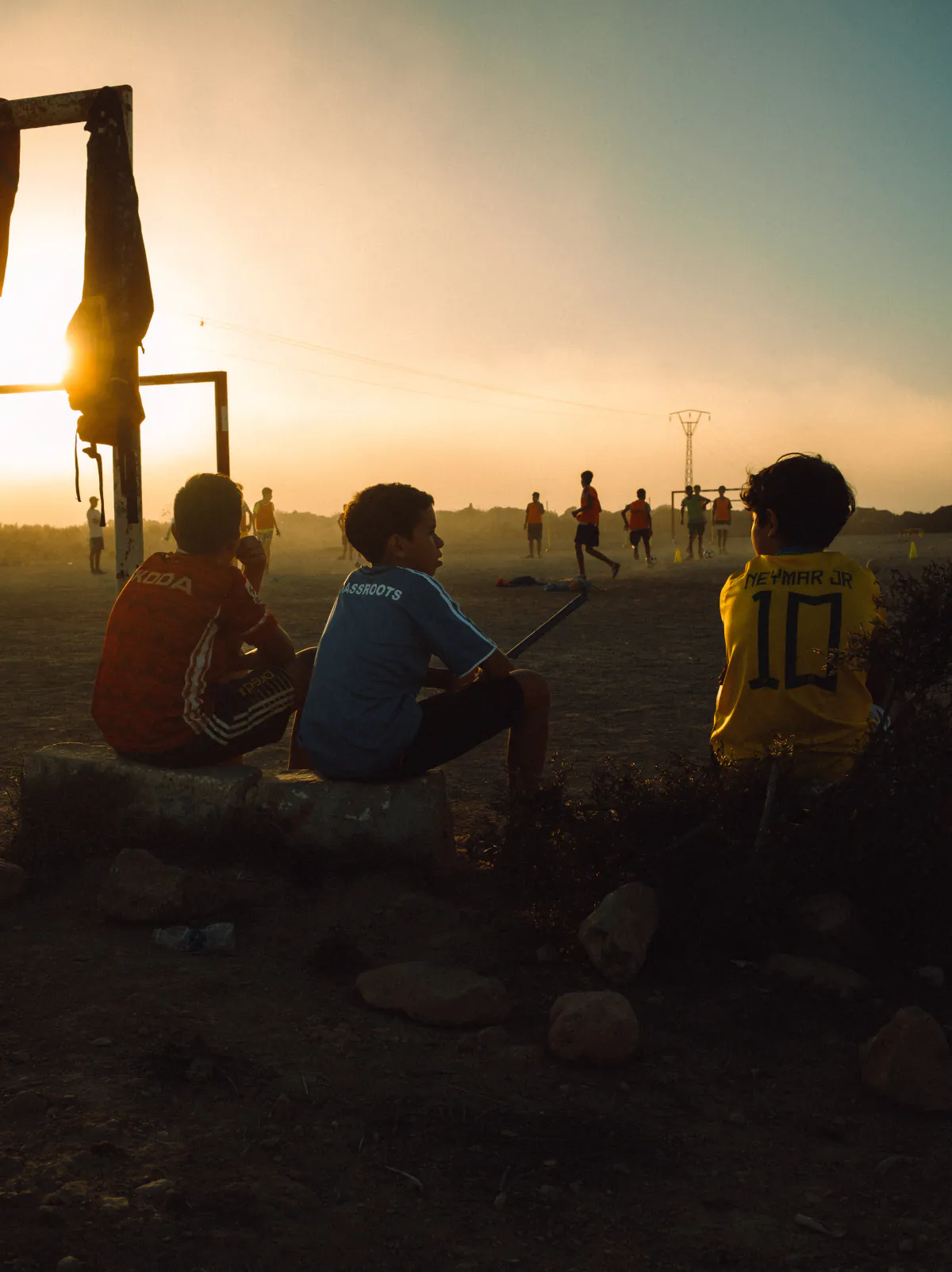 Kinder schauen bei Sonnenuntergang einem Fußballspiel zu